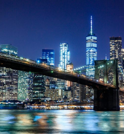 Stunning view of the Brooklyn Bridge and New York City skyline illuminated at night.