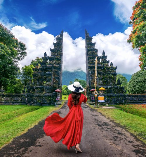 Woman walking at big entrance gate, Bali in Indonesia.